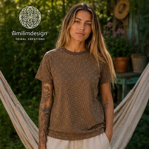 May include: A brown short-sleeved t-shirt featuring a repeating small white geometric diamond pattern. The shirt has a crew neckline and is worn with light-coloured bottoms. The logo for ilimilimdesign TRIBAL CREATIONS is visible.