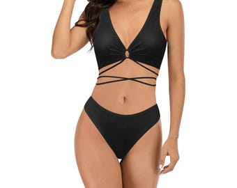 Op de afbeelding: Zwarte bikini top en broekje met een gekruist bandontwerp. De top heeft een V-hals en een ringdetail in het midden.