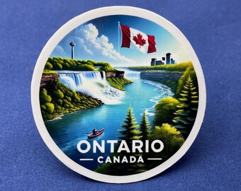 Pode incluir: Um autocolante redondo com uma ilustração cénica das Cataratas do Niágara em Ontário, Canadá. A imagem inclui uma bandeira canadiana, uma cachoeira, um rio e o texto "ONTARIO CANADA". O autocolante tem uma borda branca e está sobre um fundo azul.