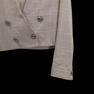 May include: A pink blazer with a white grid pattern and silver buttons. The blazer has a double-breasted closure and long sleeves.