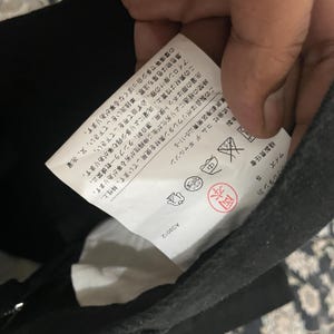 Puede incluir: Una etiqueta blanca con texto negro y s&iacute;mbolos. La etiqueta incluye instrucciones de lavado, informaci&oacute;n de tama&ntilde;o y el nombre de la marca "Comme des Gar&ccedil;ons." El texto en la etiqueta dice: "Talla: S, Supervisor de costura: Okamoto, AD2012, Limpieza en seco, 株式会社 コムデギャルソン, 東京都港区南青山5-11-5, 洗濯の際はネット使用、漂白剤、タンブラー乾燥禁止。この素材は性質上、洗濯により多少縮む事があります。アイロン掛けの際、必ず当て布をして下さい。漂色物は色落ち注意、単独洗いをして下さい。又、洗濯の摩擦等で多少白っぽくなる事があります。この製品はポリウレタン素材を使用しています。特性上、時間の経過により劣化が生じ伸縮性が劣る事があります."