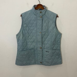 May include: A light blue quilted vest with a snap closure and a Barbour logo on the front pocket.