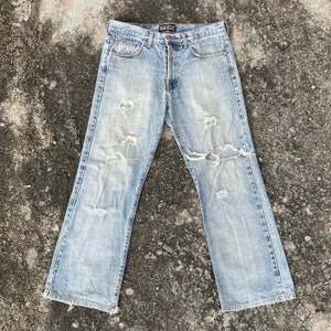 May include: Light blue distressed denim jeans with the word "BASIC" on the back waistband.