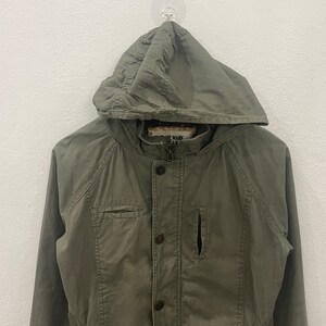 May include: A green hooded jacket with a button closure and a zipper. The jacket has a pocket on the left chest and a small pocket on the right side. The label on the jacket reads "Trade Mark Is R".