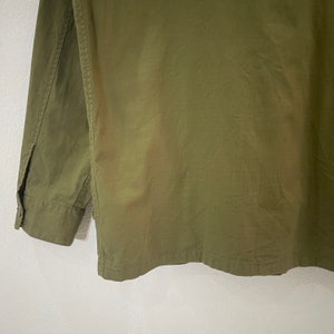 Op de afbeelding: Olijfgroen overhemd met knopen. Het shirt met lange mouwen heeft een manchet met knopen en een kleine split bij de pols. De stof heeft een licht getextureerde uitstraling. Het shirt is effen van kleur.