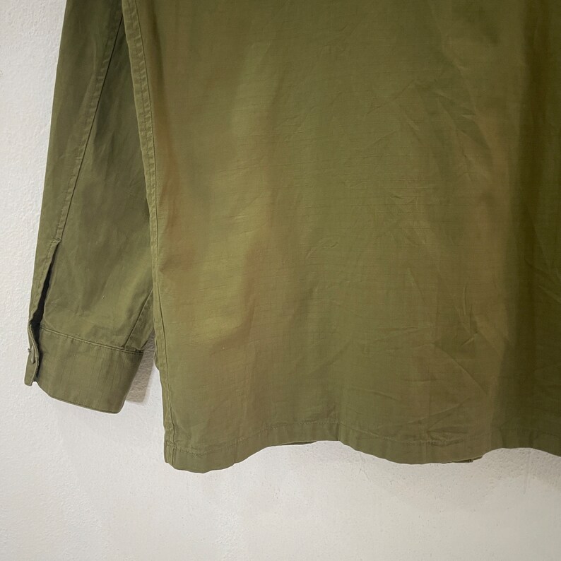 Op de afbeelding: Olijfgroen overhemd met knopen. Het shirt met lange mouwen heeft een manchet met knopen en een kleine split bij de pols. De stof heeft een licht getextureerde uitstraling. Het shirt is effen van kleur.