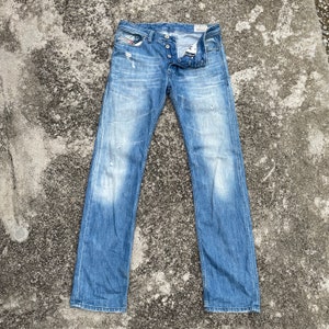 May include: A pair of light blue denim jeans with distressed details and a button fly.