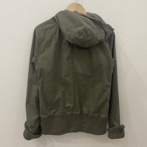 May include: A green hooded jacket with a zipper closure and a ribbed waistband.
