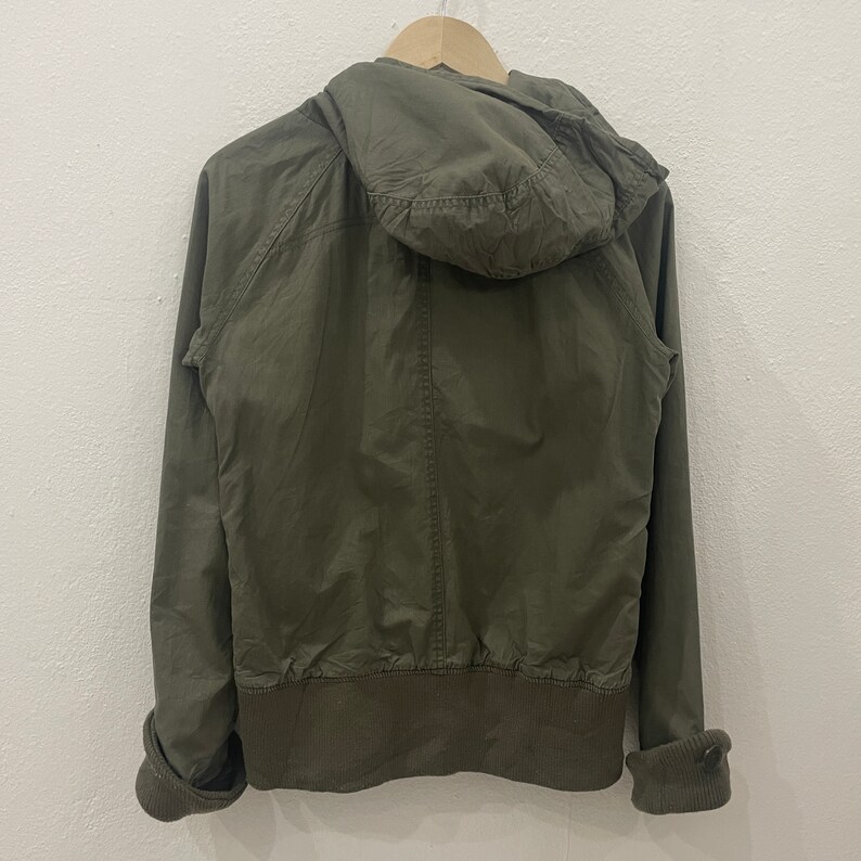 May include: A green hooded jacket with a zipper closure and a ribbed waistband.