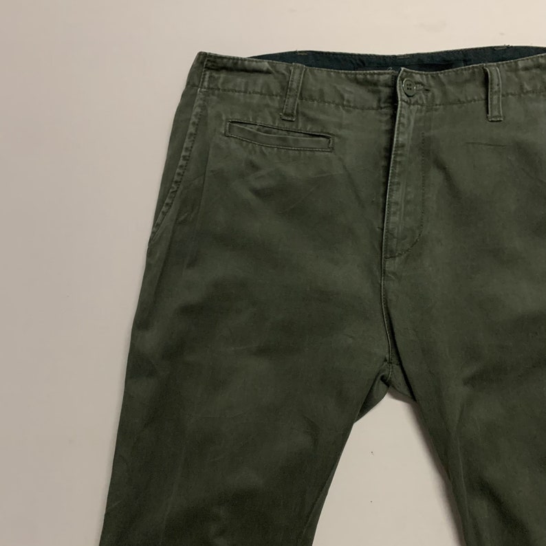 May include: A pair of dark green cargo pants with a front pocket and a button fly.