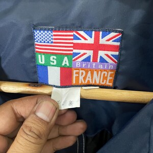 May include: A blue jacket with a patch that says "USA Britain France" with the flags of each country.