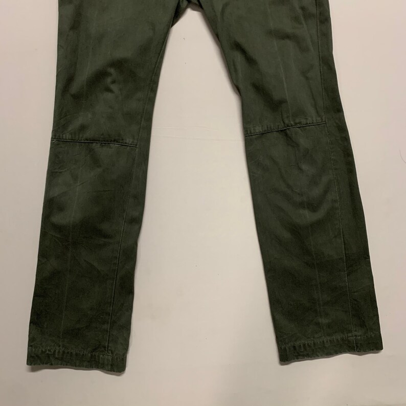 May include: A pair of dark green cargo pants with a straight leg fit. The pants have a subtle texture and are made of a durable fabric.