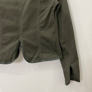 May include: A dark green utility jacket with a long sleeve and a black trim around the bottom and cuffs.