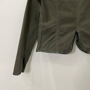 May include: A dark green cropped jacket with long sleeves and a button closure. The jacket has a slightly fitted silhouette and a collar.