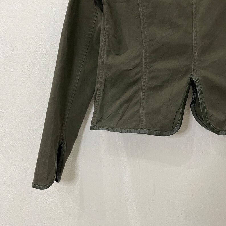 May include: A dark green cropped jacket with long sleeves and a button closure. The jacket has a slightly fitted silhouette and a collar.