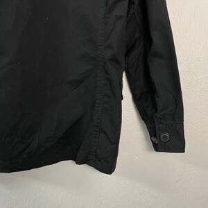 May include: Black jacket with a buttoned sleeve. The jacket has a classic design with a buttoned cuff and a tailored fit. The fabric appears to be a durable material, suitable for various weather conditions.