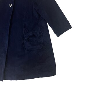 May include: A navy blue coat with a bow detail on the pocket.