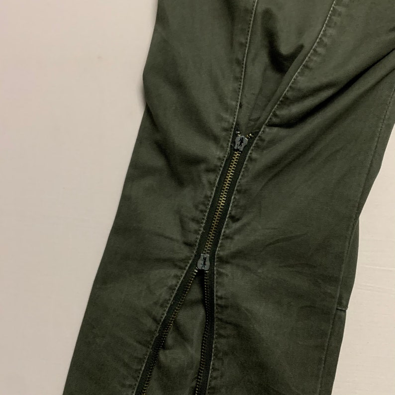 May include: A pair of dark green pants with a zipper down the center seam.