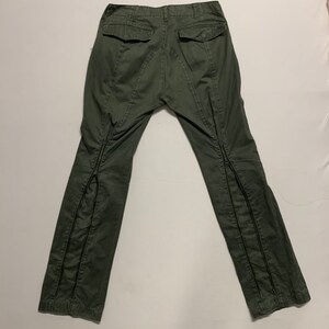 May include: A pair of dark green cargo pants with zipper details on the legs.