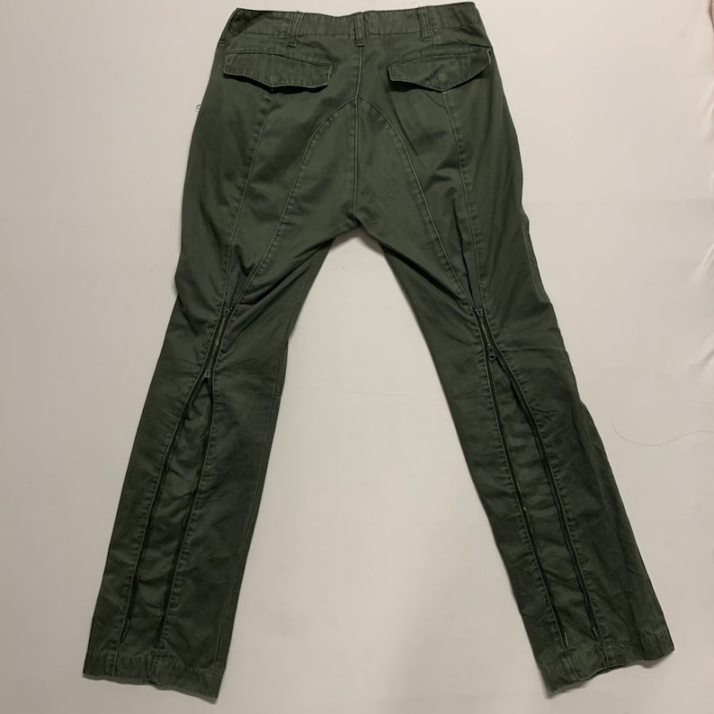 May include: A pair of dark green cargo pants with zipper details on the legs.