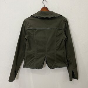 May include: A dark green utility jacket with a collar and long sleeves. The jacket has a zipper closure and a flap pocket on the chest.