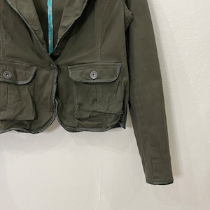 May include: A dark green cropped blazer with a collar, two pockets, and a button closure. The blazer has a slightly distressed look and is made of a soft, comfortable fabric.