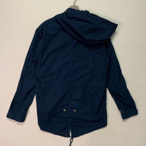 May include: A navy blue hooded jacket with a drawstring hood and waist. The jacket features a full-length zip, two front pockets, and buttoned cuffs. The jacket is made of a lightweight, durable fabric.