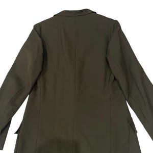 Puede incluir: Un blazer de color verde oliva s&oacute;lido que presenta un cuello con solapa de muesca, mangas largas y dos bolsillos con solapa situados en la parte inferior frontal. La prenda tiene una costura vertical central en la espalda y hombros.