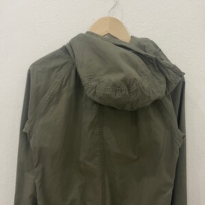 May include: A green hooded jacket with a zipper closure. The jacket is made of a lightweight fabric and has a relaxed fit.