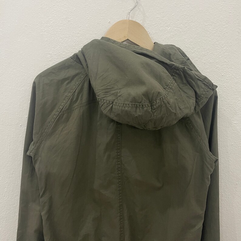May include: A green hooded jacket with a zipper closure. The jacket is made of a lightweight fabric and has a relaxed fit.