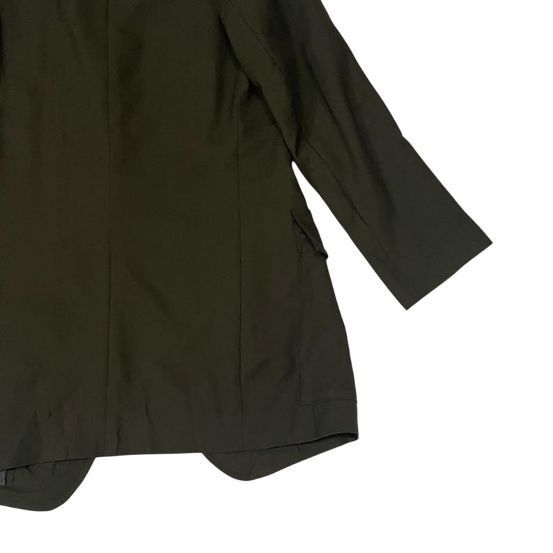 Puede incluir: Un blazer de color verde oliva oscuro s&oacute;lido con mangas largas, hombros estructurados y un bolsillo con solapa visible en el lateral. La prenda tiene un acabado mate liso con detalles de costuras verticales en el panel frontal.