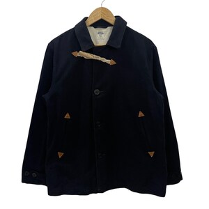 May include: A navy blue jacket with a button closure and a toggle closure. The jacket has two pockets on the front and two pockets on the inside. The jacket has a brown leather trim around the collar and pockets.