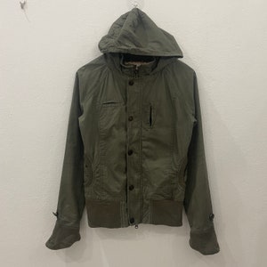 May include: A green hooded jacket with a zipper and button closure. The jacket has a ribbed hem and cuffs.