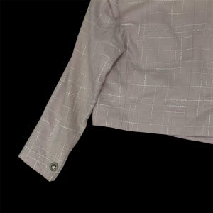 May include: A pale pink blazer with a white grid pattern. The blazer has a single button closure on the left side of the front.