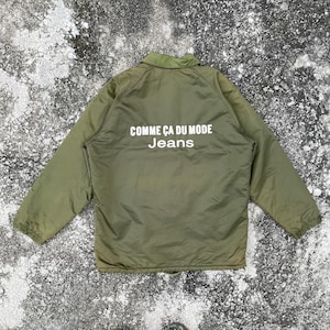 May include: A green quilted jacket with a white logo that reads "Comme Ca Du Mode Jeans".