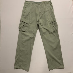 May include: Light green cargo pants with multiple pockets on the legs. The pants have a button and zipper closure and belt loops. The fabric appears to be a durable cotton blend, suitable for outdoor activities.