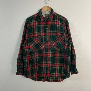 May include: A green, red, and yellow plaid flannel shirt with a button-up front and two chest pockets.
