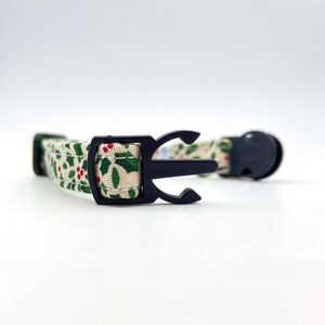 May include: A white and green patterned cat collar with a black plastic buckle.