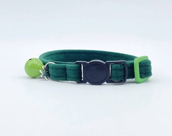 May include: A green velvet cat collar with a black plastic buckle and a green bell with a silver star charm.