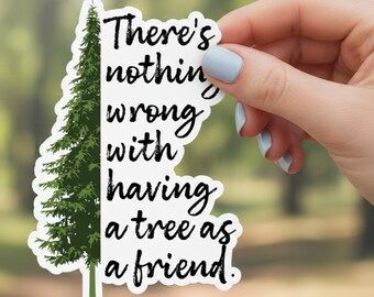 Könnte beinhalten: Ein weißer Aufkleber mit einer grünen Baumgrafik auf der linken Seite und dem Text "There's nothing wrong with having a tree as a friend" in schwarzer Schrift. Der Aufkleber wird von einer Hand mit hellblauem Nagellack gehalten.