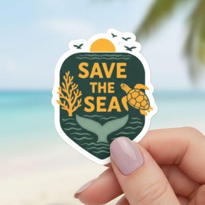 May include: A sticker with a dark green background and the words "SAVE THE SEA" in yellow. The sticker features a yellow sun, a sea turtle, a whale tail, and coral. The sticker is held by a person with a beach and ocean background.