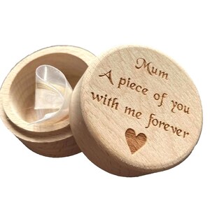 May include: A wooden keepsake box with the lid open, revealing a ribbon inside. The lid is engraved with the words "Mum, A piece of you with me forever" and a heart symbol.
