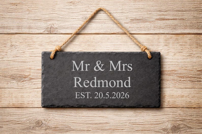 A rectangular dark grey slate plaque hangs by a twine rope against a wooden background, engraved with Mr & Mrs Redmond and EST. 20.5.2026.