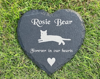 May include: A heart-shaped, dark gray slate memorial stone with the name "Rosie Bear" and the phrase "Forever in our hearts" in white lettering. A white cat silhouette and a white heart are also featured.