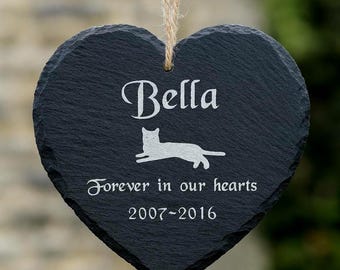May include: A heart-shaped, black slate memorial plaque with a natural twine hanger. The plaque features the name "Bella", a cat silhouette, and the inscription "Forever in our hearts 2007-2016" in white lettering.