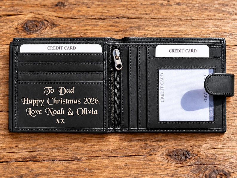 May include: A black bi-fold wallet featuring multiple credit card slots, a clear ID window, and a central zippered compartment. The interior is engraved with the text: To Dad, Happy Christmas 2026, Love Noah & Olivia, XX. The wallet includes a snap closure.