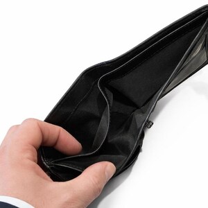 Hand holding open the empty black fabric-lined bill compartment of a black leather wallet.