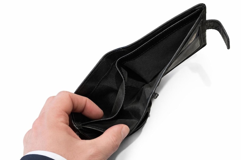 Hand holding open the empty black fabric-lined bill compartment of a black leather wallet.