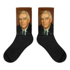 Könnte beinhalten: Ein Paar schwarze Socken mit einem bunten Bild eines Mannes im Anzug und Krawatte. Das Bild befindet sich auf der Oberseite der Socken, der Rest der Socken ist schwarz.