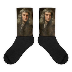 Könnte beinhalten: Ein Paar schwarze Socken mit einem Porträt von Isaac Newton auf der Oberseite jeder Socke. Das Porträt ist eine Nahaufnahme von Newtons Gesicht und Schultern, und er trägt eine dunkelbraune Jacke.